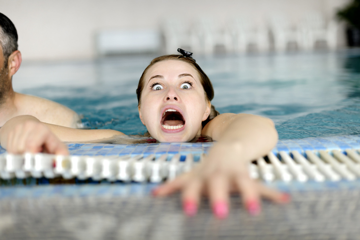 Woman reaching out of the pool scared