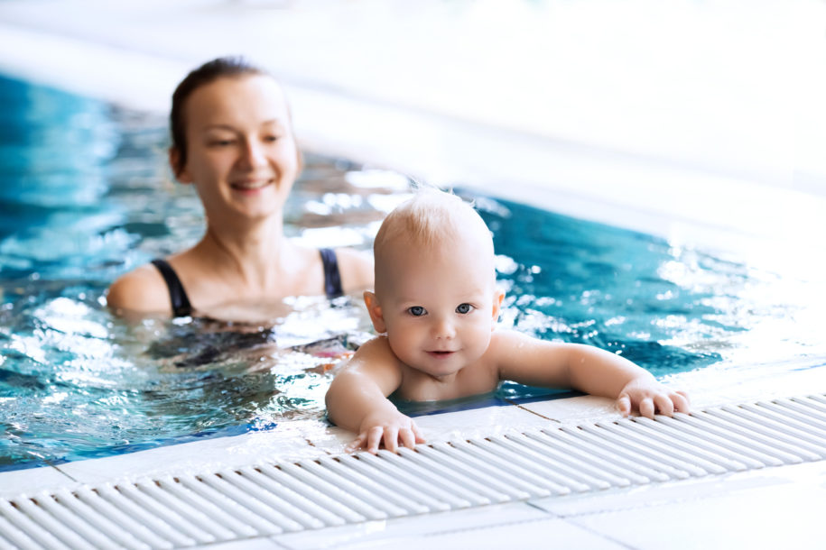 Mother teaching baby to swim in a swimming pool.