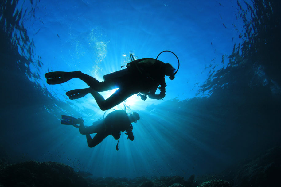 Two people scuba diving with sunlight from above