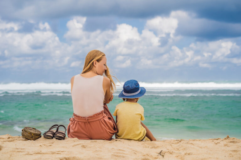 Mom and son travelers on amazing Melasti Beach with turquoise water, Bali Island Indonesia. Traveling with kids concept