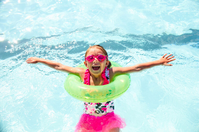 Happy little girl wearing flotation ring in pool
