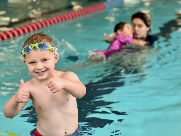 child thumbs up at swim lessons
